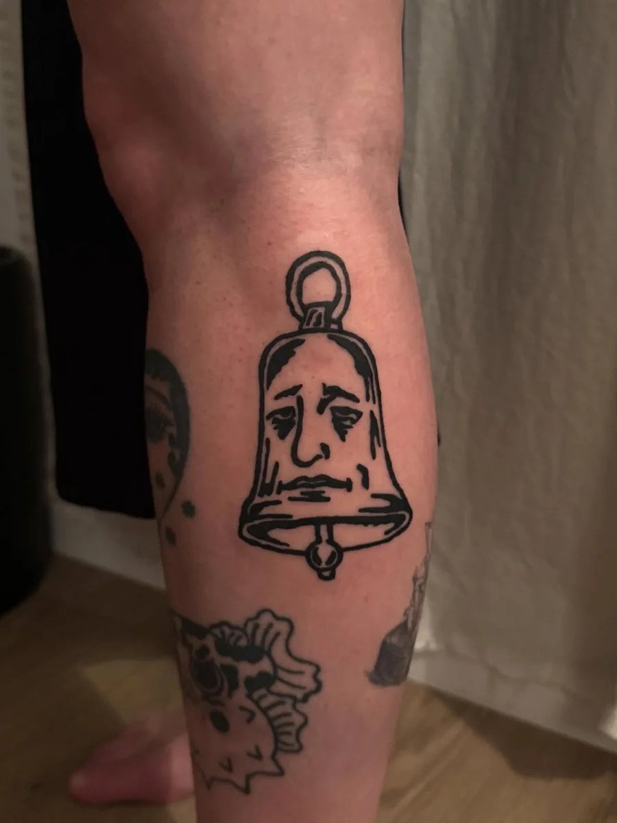 A black illustrative handbell with a melancholy face on the calf.