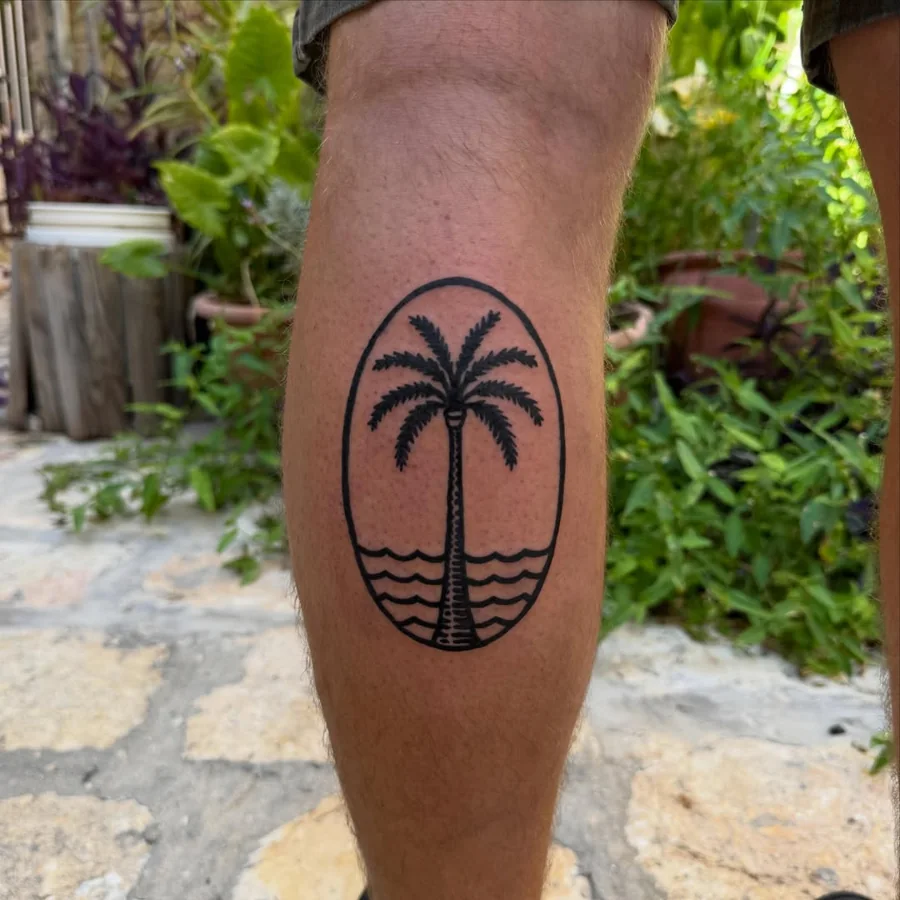 A palm tree, setting sun, and horizontal water lines within an oval on the calf.