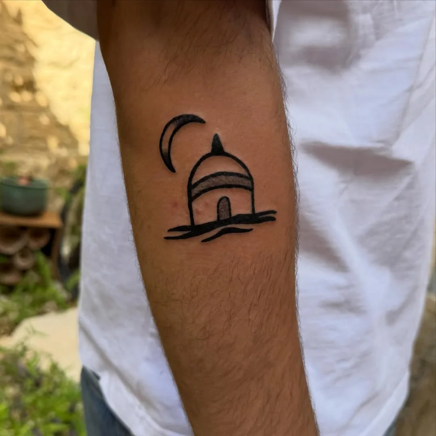 A small domed building with a crescent moon in bold black lines on the inner arm.