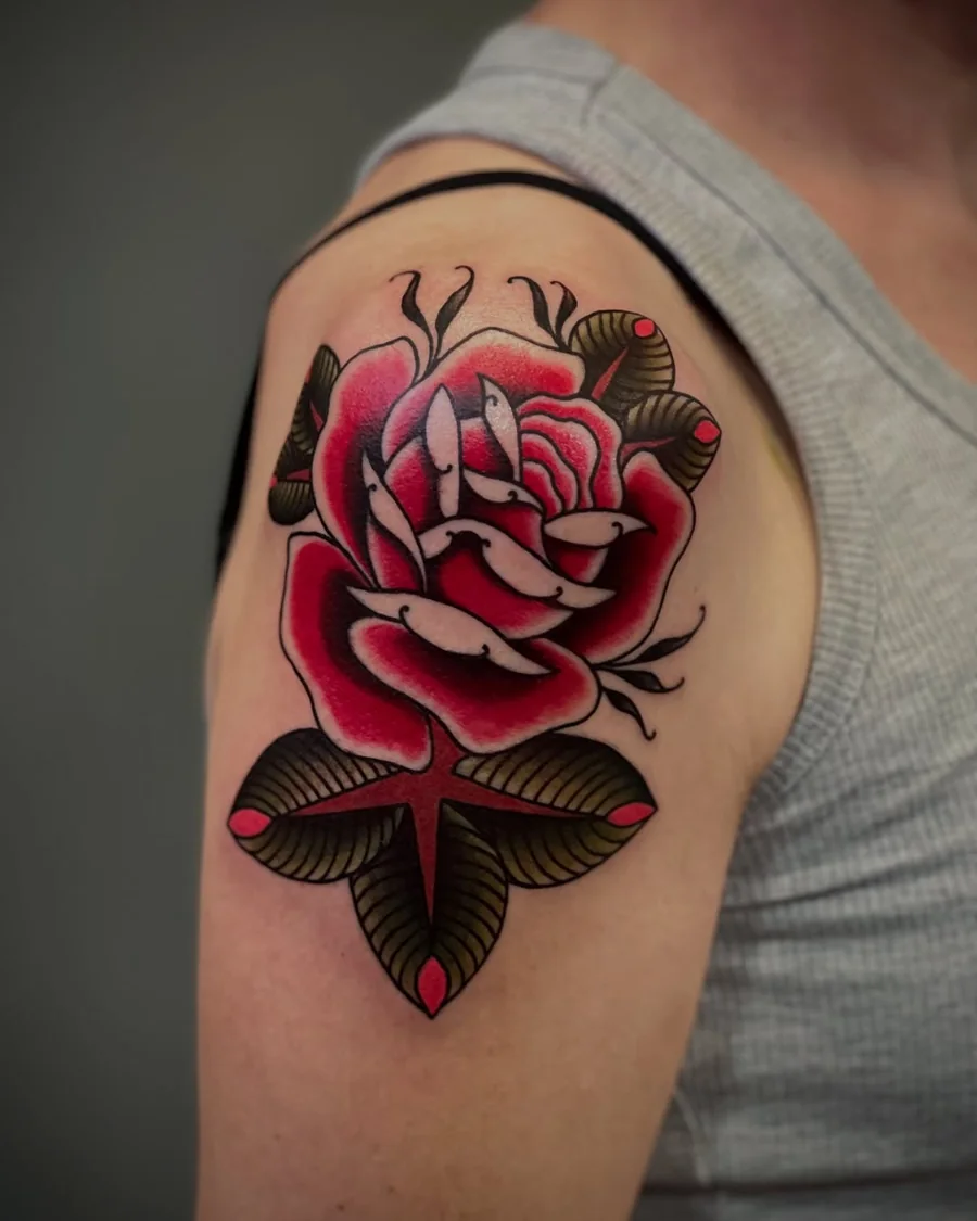 A large traditional red rose with dark green leaves on the upper arm.
