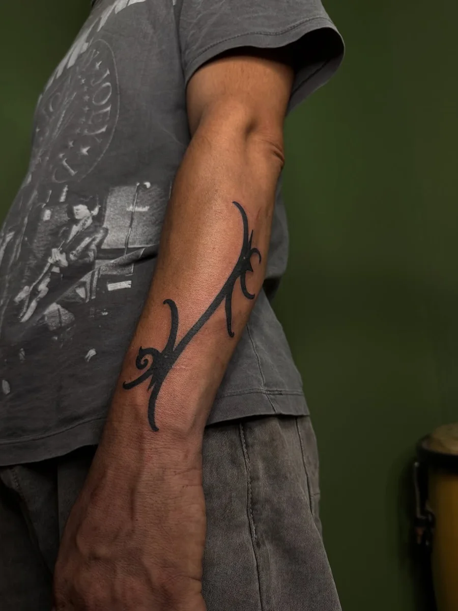 Flowing tribal blackwork tattoo on the forearm by Yonatan