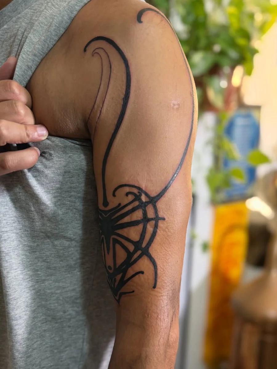 Curving tribal blackwork tattoo on the shoulder and upper arm by Yonatan